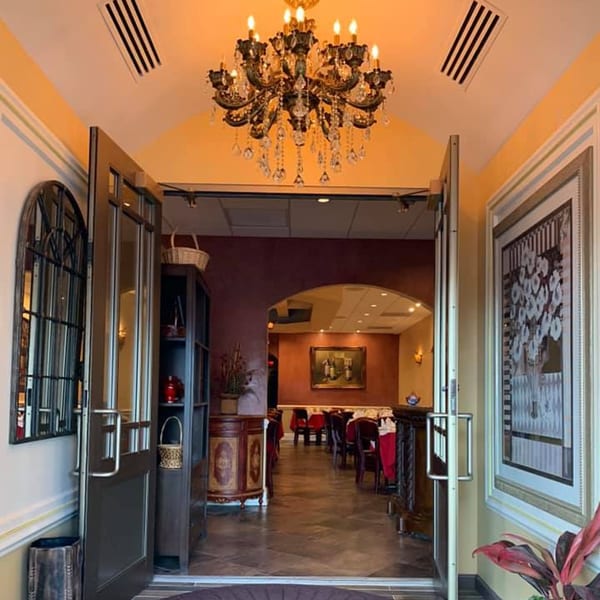 Entrance to Stefano's Restaurant with an ornate chandelier, open doors, and a glimpse of dining tables.