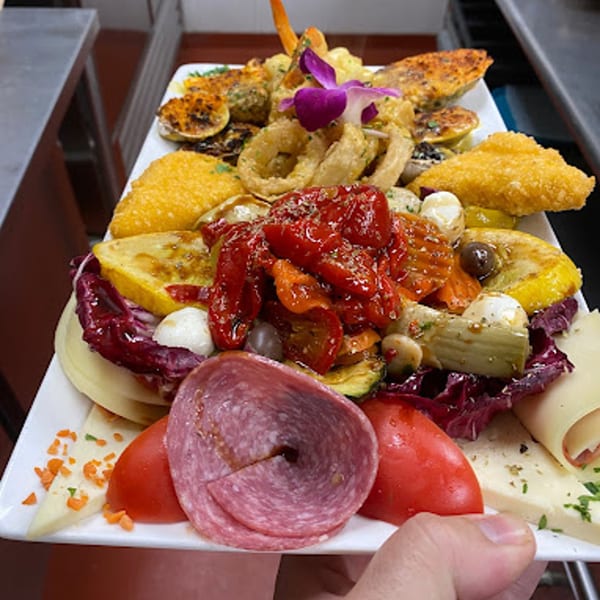 A large platter of Italian appetizers including fried calamari, roasted peppers, salami, and cheeses.